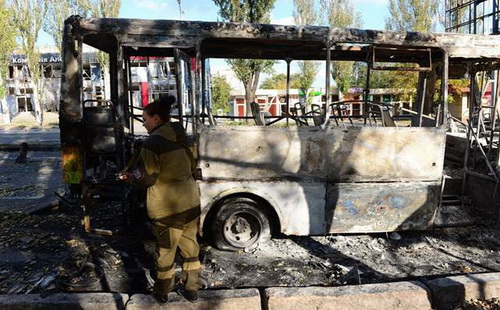 Осень в Донецке. Женщина с автоматом возле автобуса,
сгоревшего в результате артобстрела.